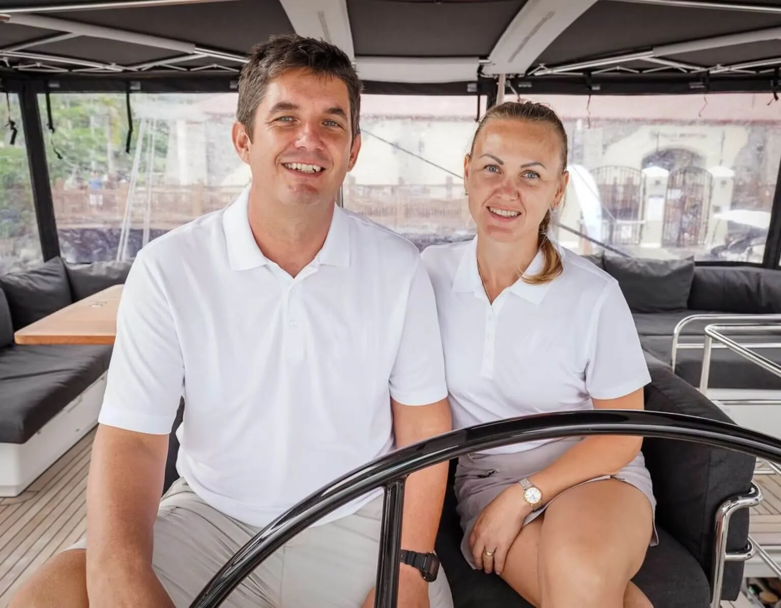 Mymlan crew smiling at the helm in matching white polos